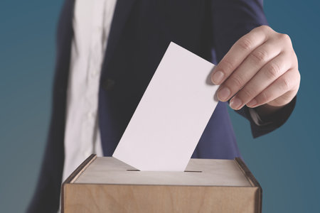 Woman putting her vote into ballot box on gradient color background, closeupの写真素材