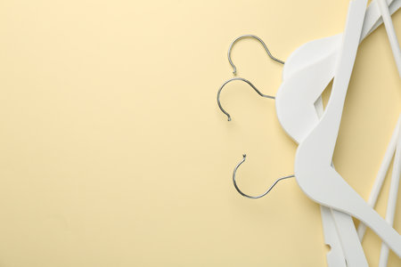 White hangers on pale yellow background, top view. Space for textの写真素材