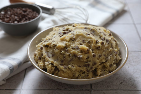 Chocolate chip cookie dough in bowl on tiled table, closeupの写真素材