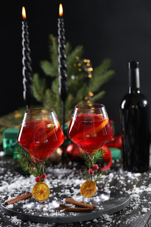 Christmas Sangria cocktail in glasses, burning candles and snow on dark wooden tableの写真素材