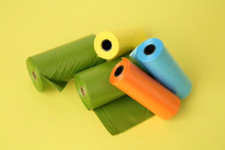 Colorful dog waste bags on yellow background, above viewの写真素材
