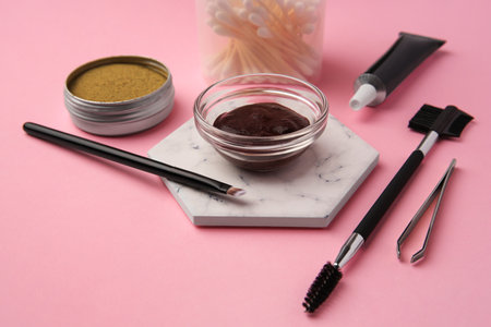 Eyebrow henna and tools on pink background