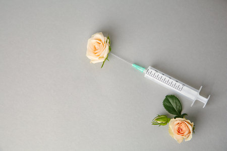 Medical syringe and beautiful roses on gray background, flat lay. Space for textの写真素材