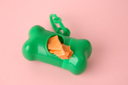 Dispenser with dog waste bags on pink background, closeup. Space for textの写真素材
