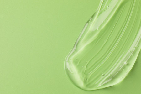 Smear of clear cosmetic gel on light green background, top view. Space for textの写真素材