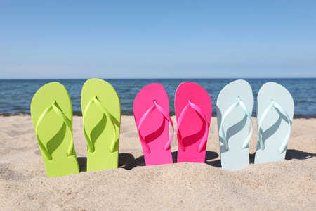Stylish colorful flip flops on beach sandの写真素材