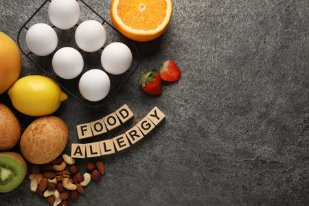 Food allergy. Different fresh products and wooden cubes on gray table, flat lay with space for textの写真素材