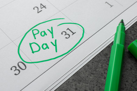 Calendar page with marked payday date and green marker on table, closeupの写真素材