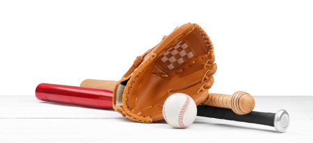 Baseball glove, bats and ball on wooden table against white backgroundの写真素材