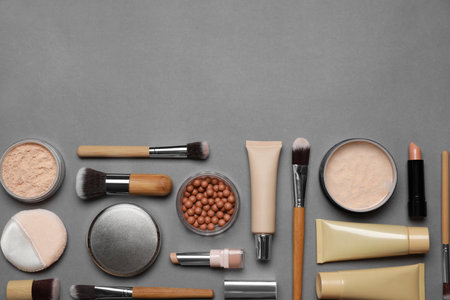 Face powders and other makeup products on gray background, flat lay. Space for textの写真素材