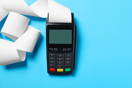 Payment terminal with thermal paper for receipt on light blue background, top view. Space for textの写真素材