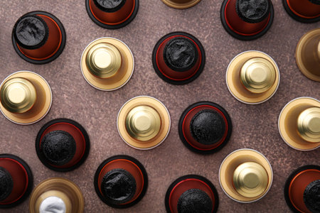 Many coffee capsules on brown table, flat lay