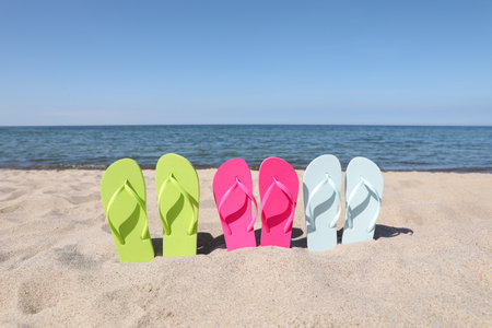 Stylish colorful flip flops on beach sandの写真素材