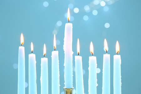 Hanukkah celebration. Burning candles on light blue background with blurred lights, closeupの写真素材