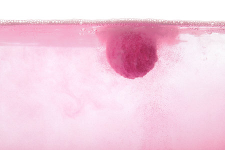 Pink bath bomb in water on white backgroundの写真素材