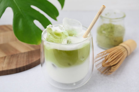 Glass of tasty iced matcha latte, leaf and bamboo whiskey on white table, closeupの写真素材
