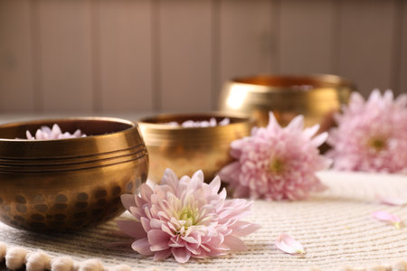 Tibetan singing bowls with water and beautiful flowers on table, space for textの写真素材