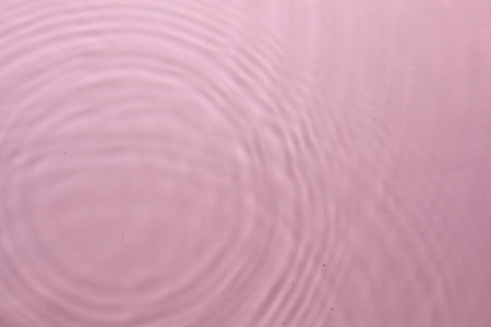 Rippled surface of clear water on pink background, top viewの写真素材