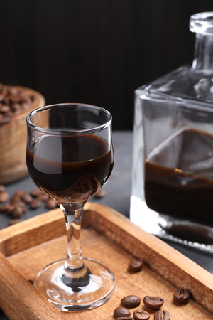 Coffee liqueur and beans on gray table, closeup