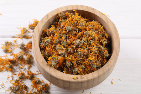 Dry calendula flowers in bowl on white wooden table, closeupの写真素材
