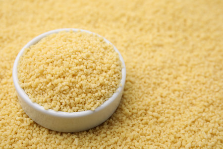 Bowl with raw couscous as background, closeup. Space for textの写真素材