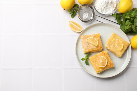 Tasty lemon bars with mint on white tiled table, flat lay. Space for textの写真素材