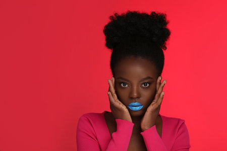 Fashionable portrait of beautiful woman with bright makeup on coral background, space for textの写真素材