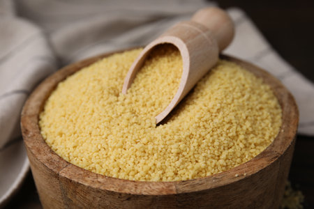 Bowl and scoop with raw couscous on table, closeupの写真素材