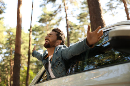 Enjoying trip. Happy man leaning out of car window, low angle viewの写真素材