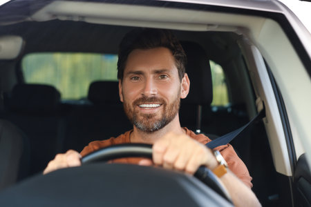 Enjoying trip. Happy bearded man driving car, view through windshieldの写真素材
