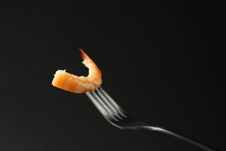 Fork with tasty shrimp on black background, space for textの写真素材