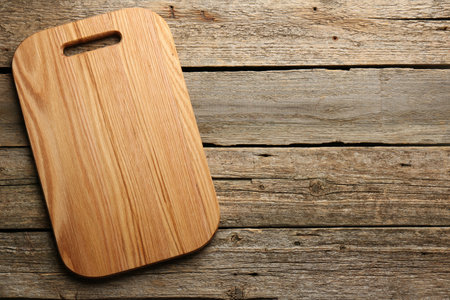 One new cutting board on old wooden table, top view. Space for textの写真素材