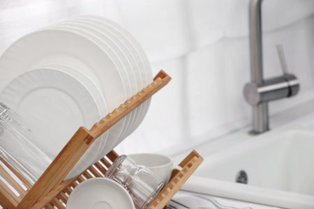 Drying rack with clean dishes in kitchen, closeup. Space for textの写真素材