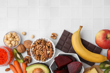 Many different products on white tiled table, flat lay with space for text. Natural sources of serotoninの写真素材