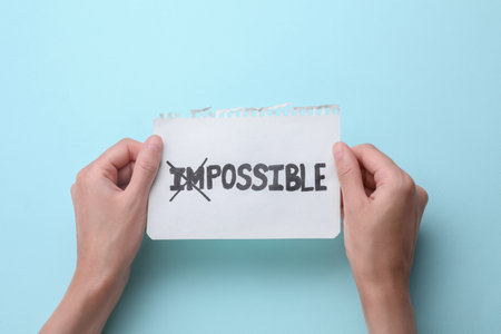 Motivation concept. Woman holding paper with changed word from Impossible into Possible by crossing...