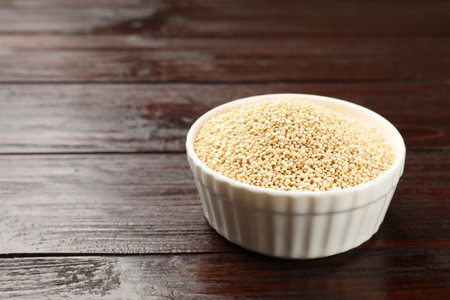 Dry quinoa seeds in bowl on wooden table, space for textの写真素材