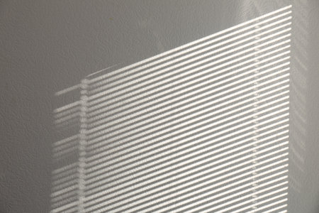 Light and shadow from window on white wall, space for text
