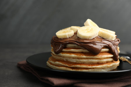 Tasty pancakes with chocolate spread and sliced banana on table against gray background, closeupの写真素材