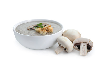 Delicious mushroom cream soup with croutons in bowl and mushrooms isolated on whiteの写真素材