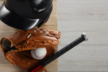 Baseball bat, batting helmet, leather glove and ball on wooden bench indoors, top view. Space for textの写真素材