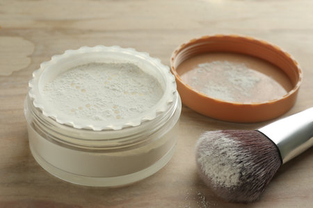 Rice loose face powder and makeup brush on brown table, closeup