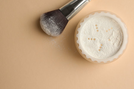 Rice loose face powder and makeup brush on beige background, flat lay. Space for textの写真素材