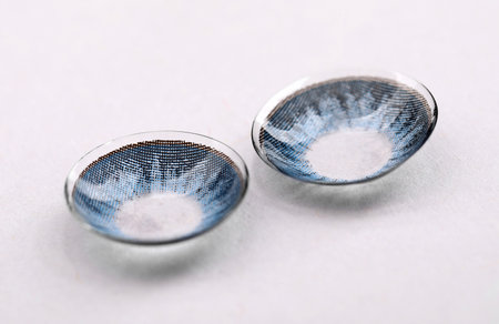 Two blue contact lenses on white background