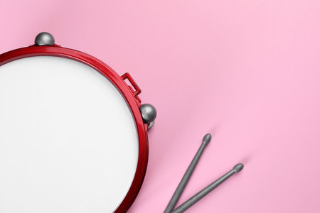 Children's drum with drumsticks on pink background, top view. Space for textの写真素材