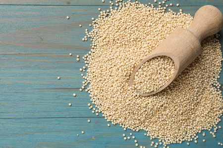 Scoop and dry quinoa seeds on light blue wooden table, top view. Space for textの写真素材