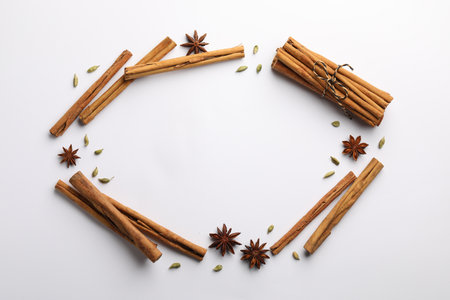 Frame made of cinnamon sticks, star anise and cardamom pods on white background, flat layの写真素材