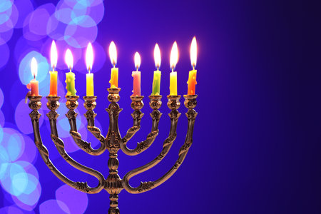 Hanukkah celebration. Menorah with burning candles on blue background with blurred lights, space for textの写真素材