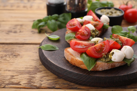 Delicious Caprese sandwiches with mozzarella, tomatoes, basil and pesto sauce on wooden table, closeup. Space for textの写真素材