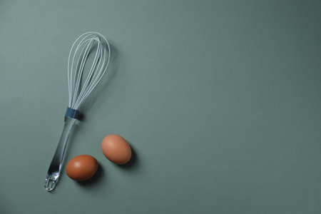 Whisk and raw eggs on pale blue background, flat lay. Space for textの写真素材