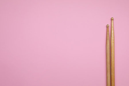Two wooden drum sticks on pink background, top view. Space for textの写真素材